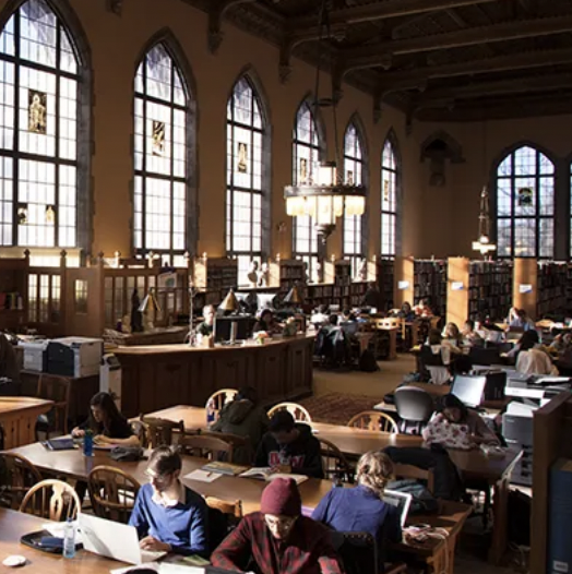 students study at rows of tables in high-ceilinged room