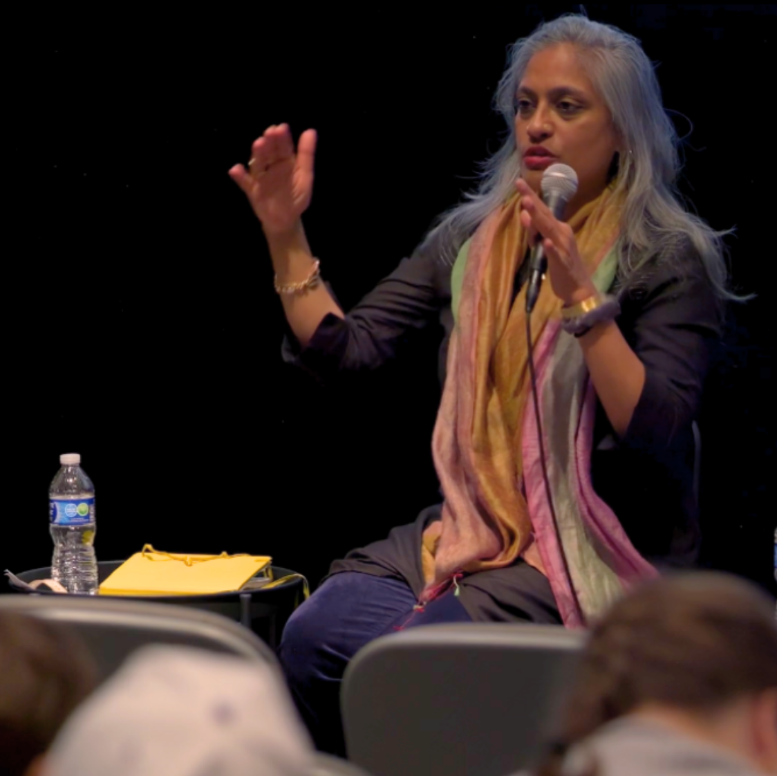 Chitra Ganesh gesticulates as she speaks into microphone in Block auditorium