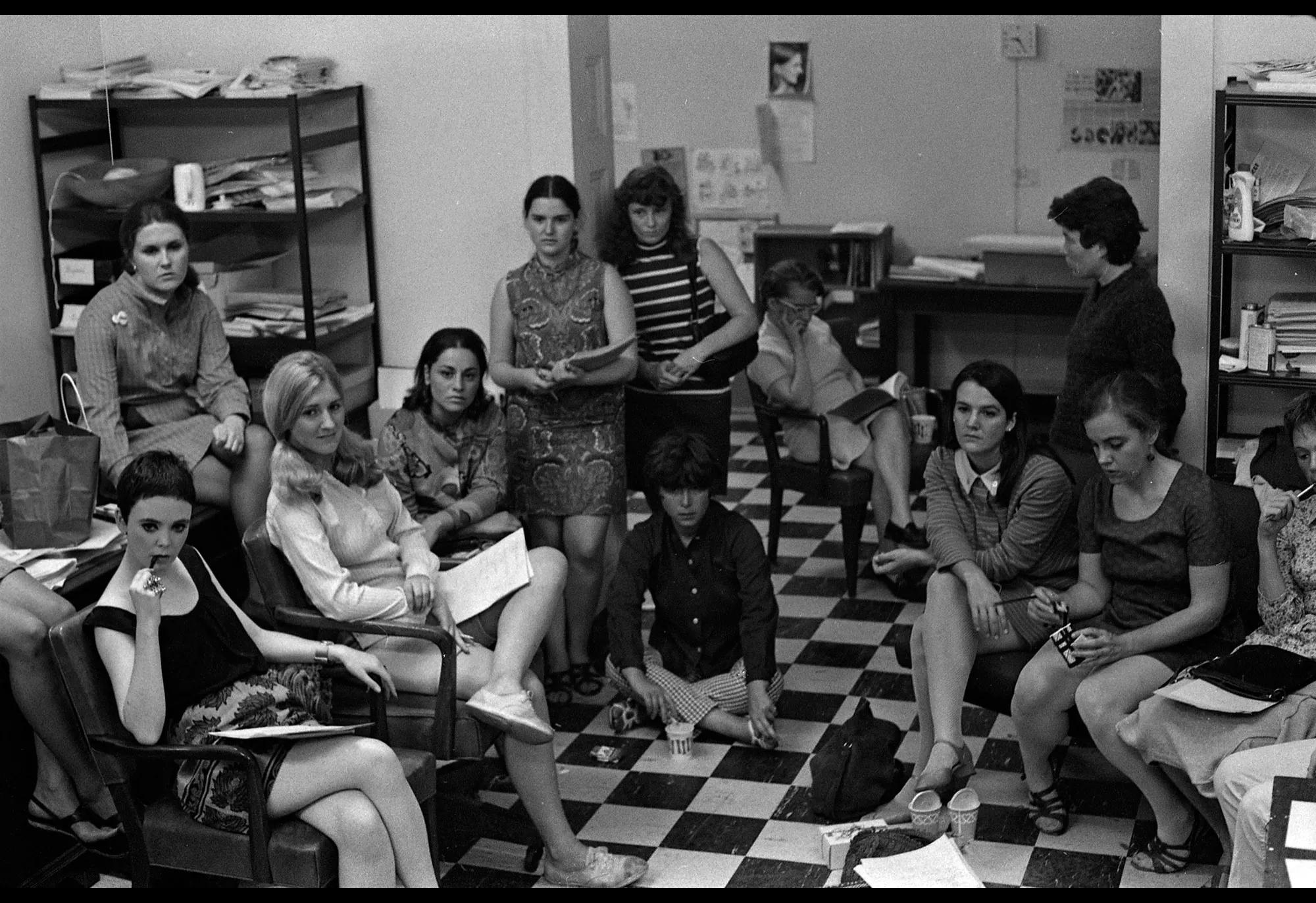 A group of women sit in a room, gazing off-camera in a photograph by Bev Grant