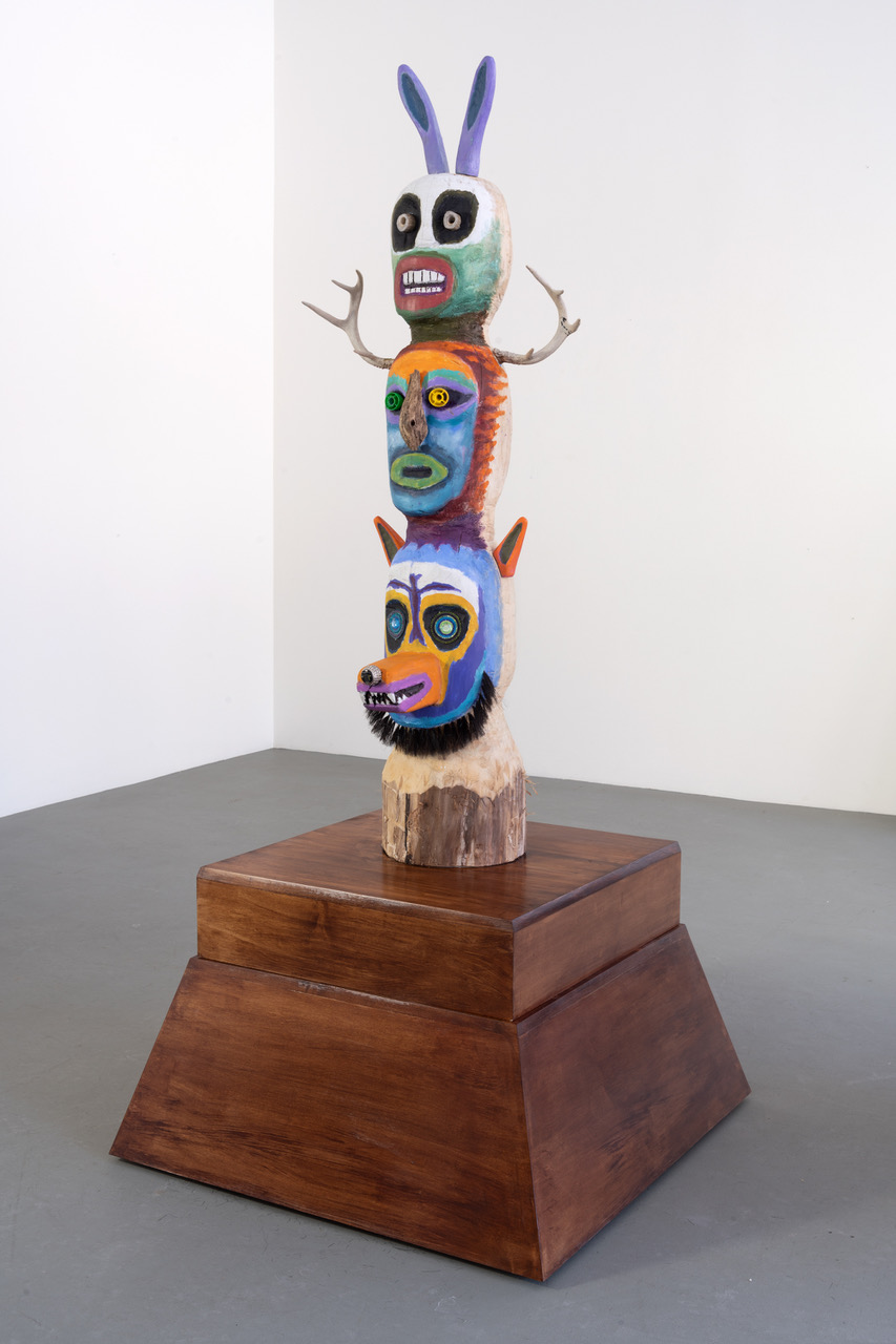 Another angle of totem comprised of three stacked renderings of animal heads on dark wood base