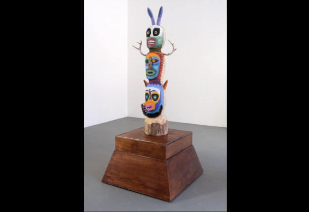 Another angle of totem comprised of three stacked renderings of animal heads on dark wood base