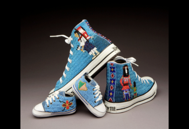two pairs of tennis shoes with figures and symbols detailed on in bead work