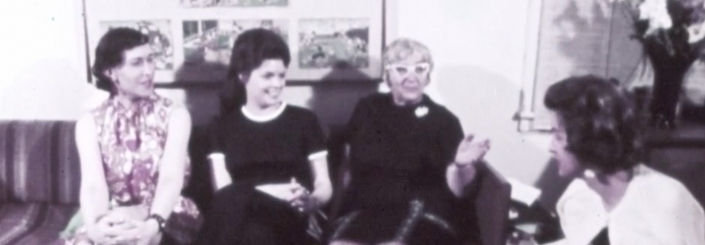 An image of a group of women sit on a couch chatting and laughing