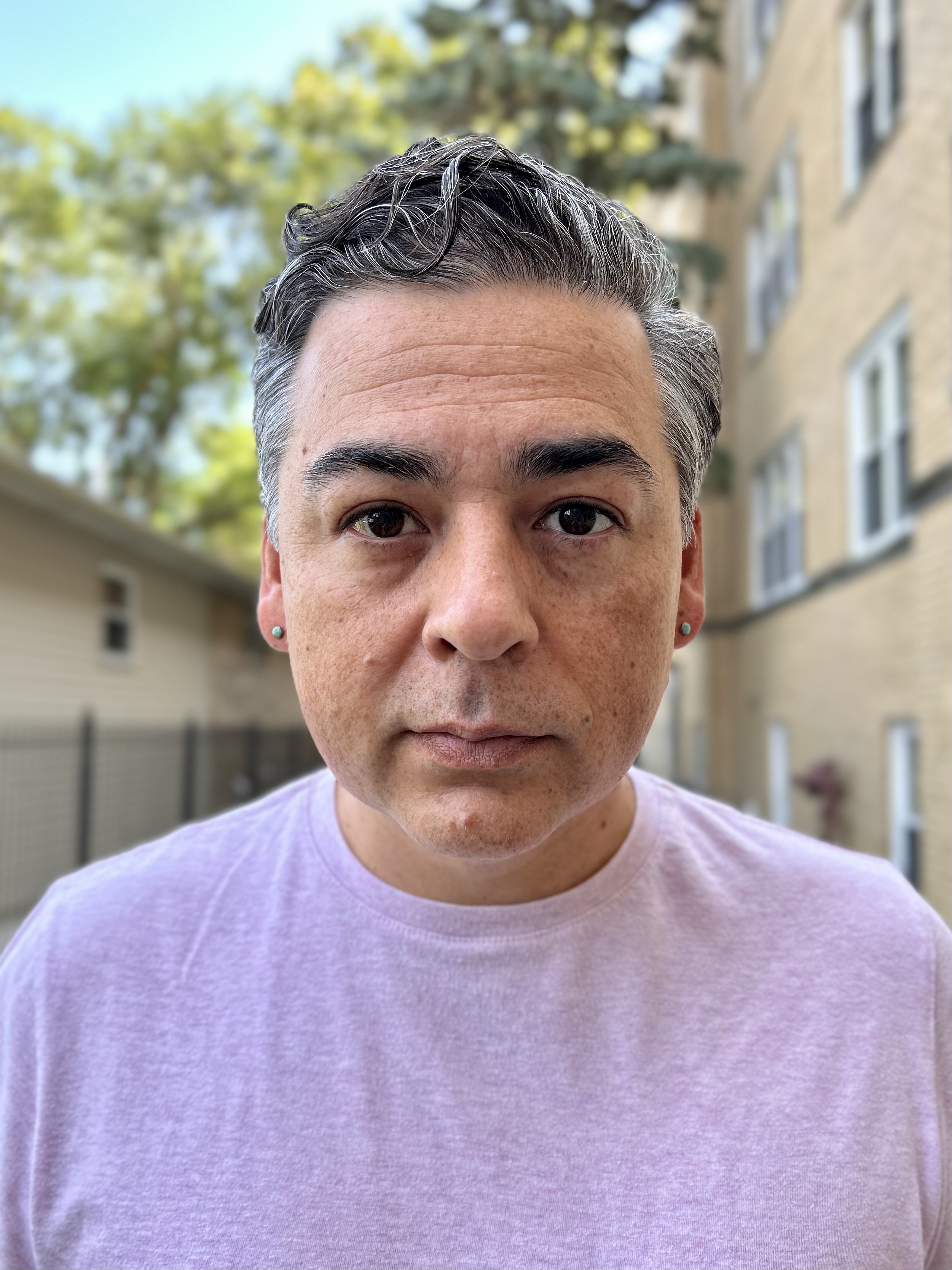 Seneca man with short grey hair in a lavender shirt, outside