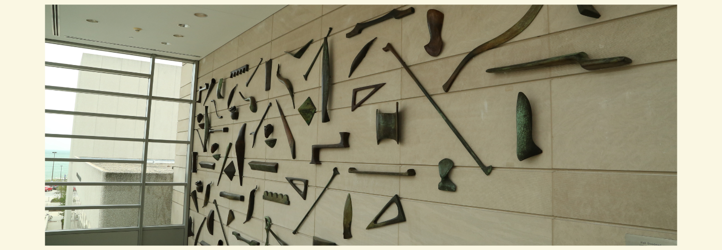 iron objects, including tools and bones, arranged in a triangular shape on a wall
