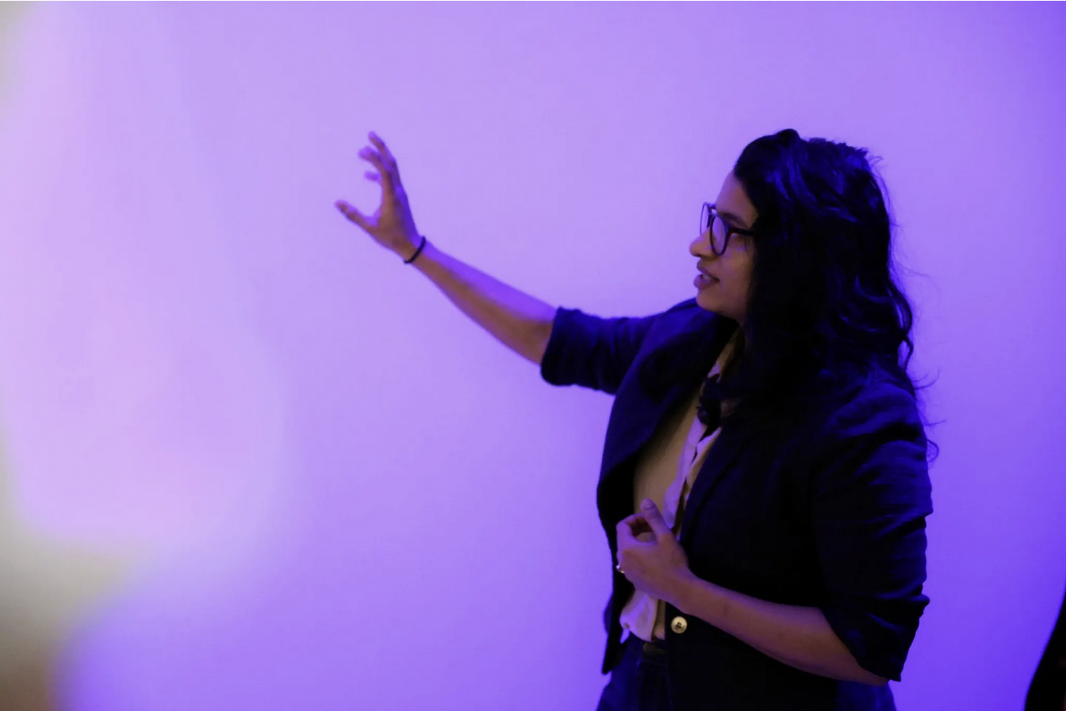 Block Museum curatorial fellow Ashley Deosoran gestures toward art in purple-lit gallery