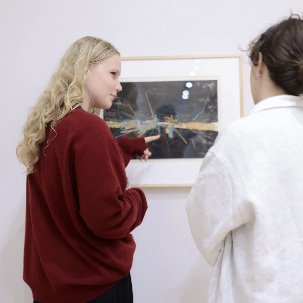 students point at framed print in Block exhibition